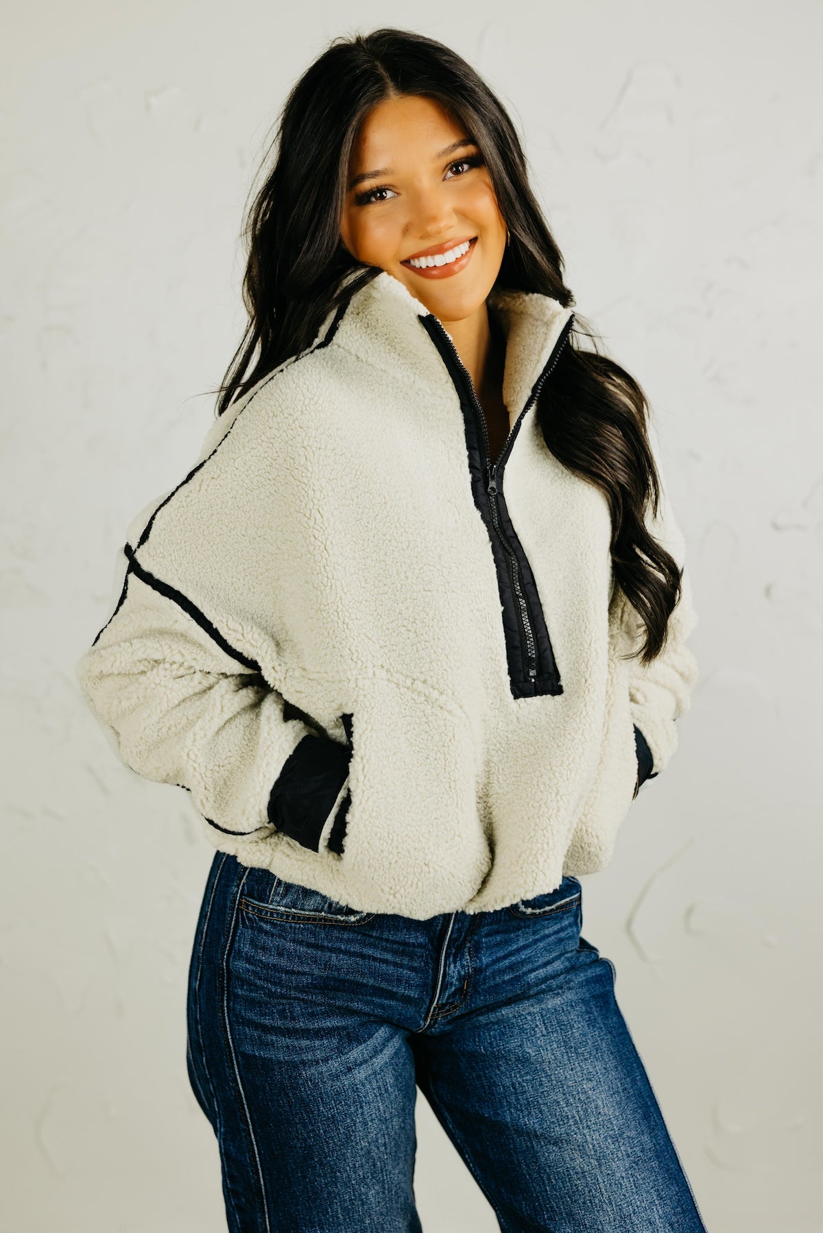 Woman wearing a white fleece pullover with black trim against a plain background