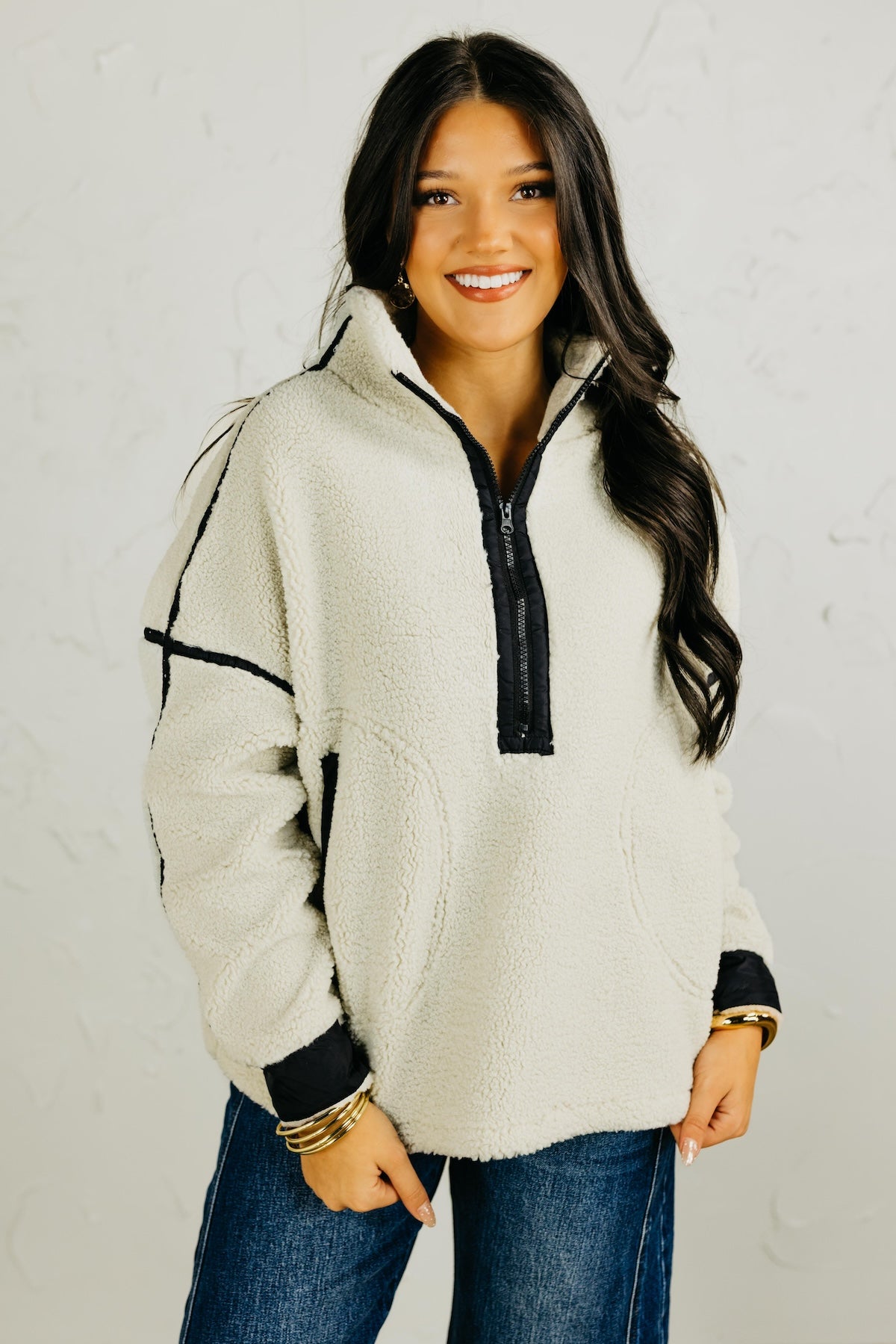 Woman wearing a white fleece pullover with black accents against a plain background
